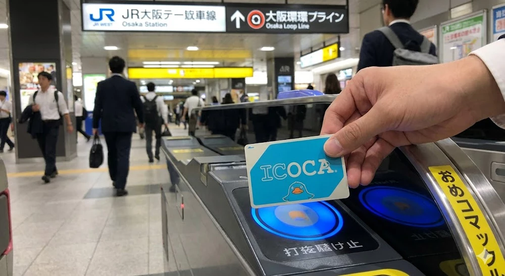 Traveler using a blue ICOCA IC card at a ticket gate in JR Osaka Station.